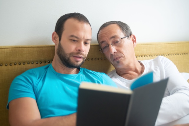 Two men reading a book together