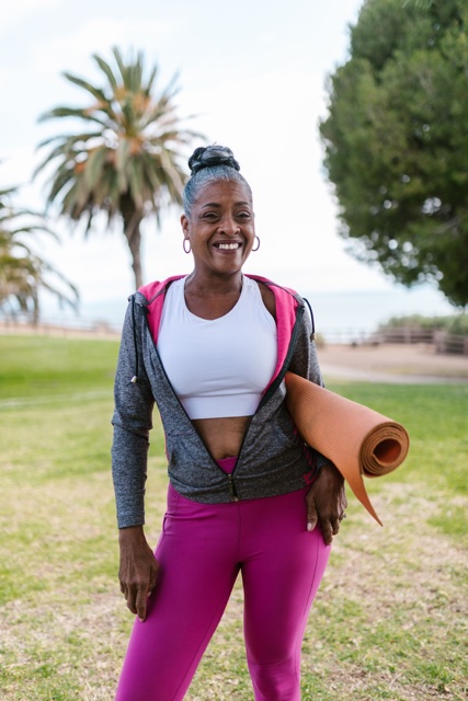 Woman outdoors holding a yoga mat