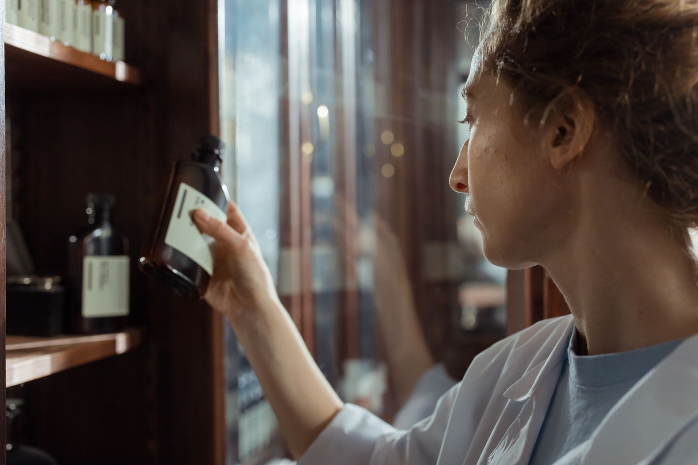 Pharmacist selecting a bottle from a pharmacy shelf